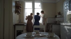 Three women look out of a window in a scene from The Zone of Interest