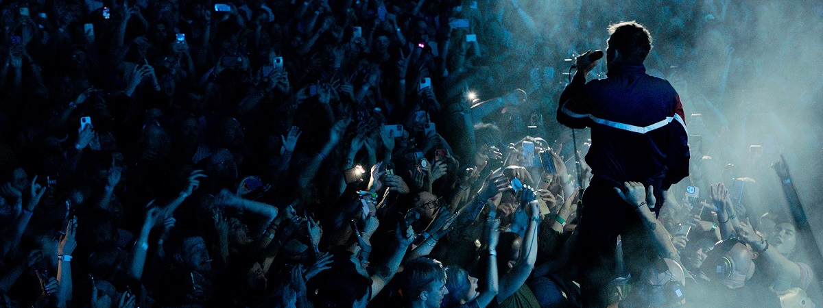 Damon Alburn sings as a crowd watches on in a promotional image for blur: Live At Wembley Stadium