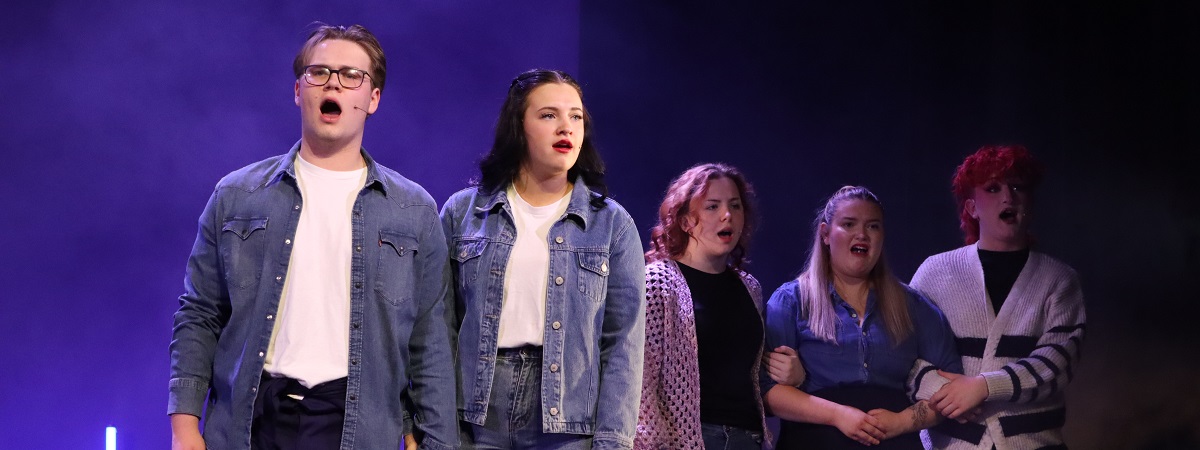 Five students from New College Durham sing on stage.