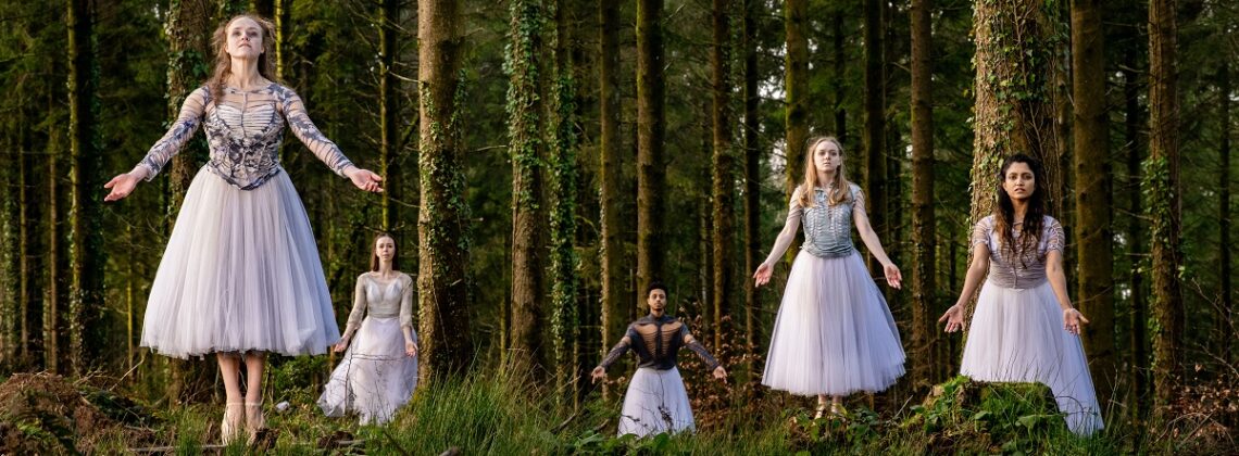 Five dancers hold a pose as if levitating in a forest in a promotional image for Ballet Cymru's Gisele.