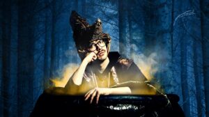 Edy Hurst sits in a cauldron wearing a witch's hat with trees in the background.