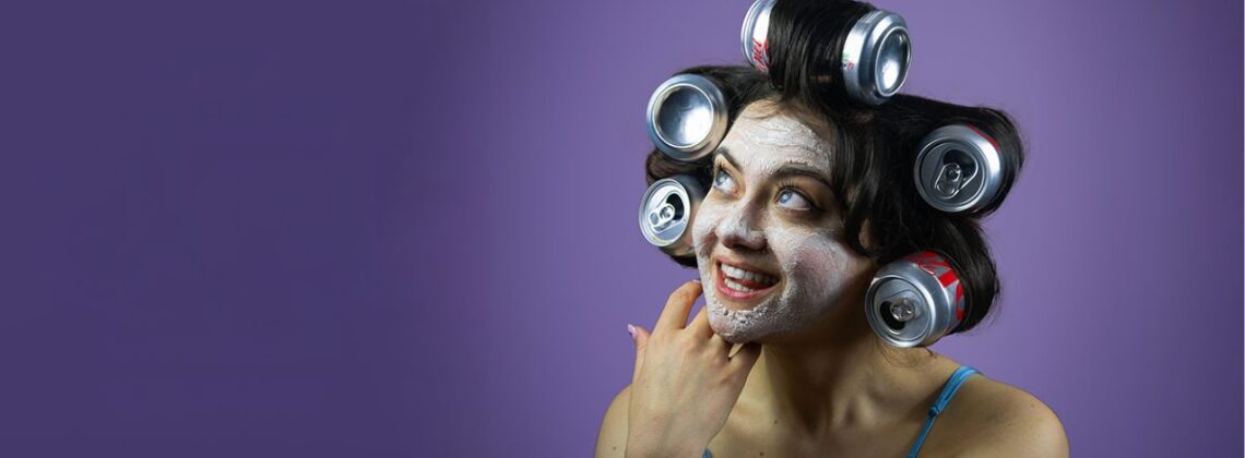 A person wearing cans in their hair as rollers with a face mask in a promotional image for Post Traumatic Slay Disorder