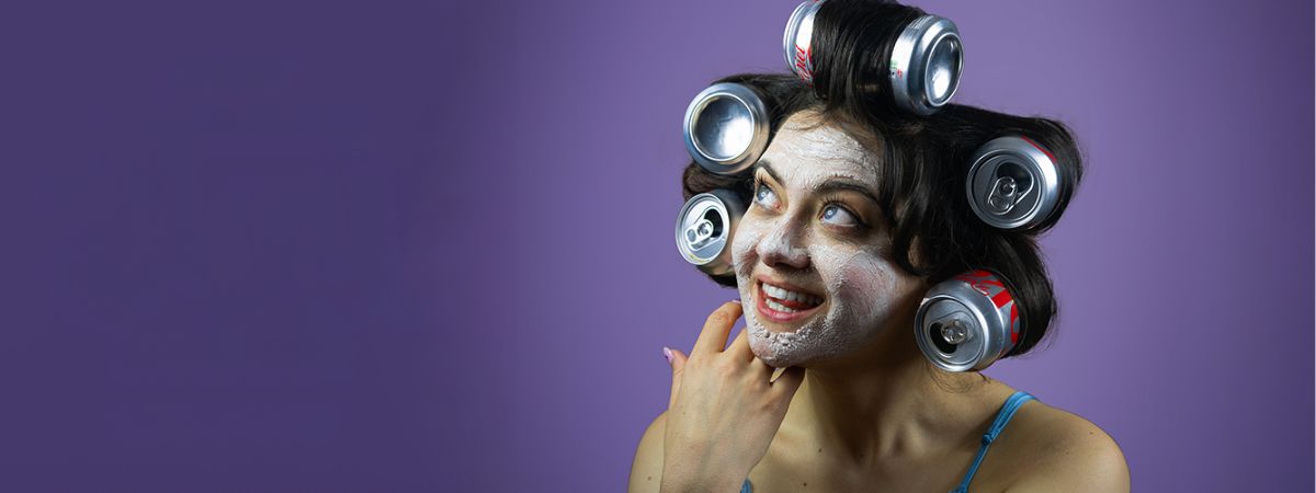 A person wearing cans in their hair as rollers with a face mask in a promotional image for Post Traumatic Slay Disorder