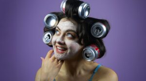 A person wearing cans in their hair as rollers with a face mask in a promotional image for Post Traumatic Slay Disorder