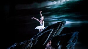 The White Swan stands a top a black rock in a promotional still from Royal Ballet's Swan Lake.